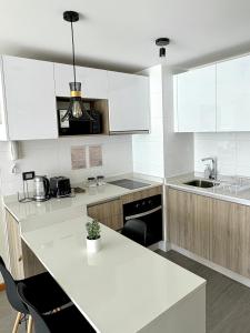 Nuevo departamento en peninsula- cavancha في إكيكي: مطبخ بدولاب بيضاء وقمة بيضاء +صورتان