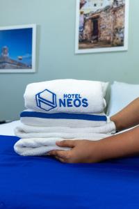 a woman is holding a stack of towels on a bed at Neos Hotel Cartagena in Cartagena de Indias