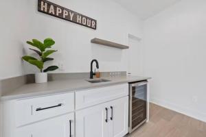 una cucina con lavandino e un cartello dell'happy hour sul muro di Jungle House Luxury Homes - Columbus Downtown Short North - Near Convention Center & Nationwide Arena - Sleeps up to 15 - Free Parking - Over 5,800 Five Stars a Columbus
