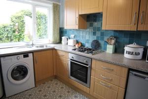 a kitchen with a stove and a washing machine at Holmlea Cottage in Freuchie