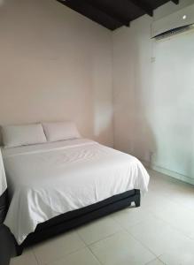 una camera da letto con un letto bianco con lenzuola bianche di La Cabana de Isaac Boquilla a Cartagena de Indias Altre 5 foto