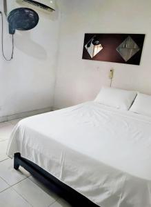 un letto bianco in una camera bianca con lampada di La Cabana de Isaac Boquilla a Cartagena de Indias
