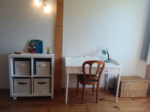 Un escritorio con una silla al lado de una mesa con un armario. en Chambre calme et verdure, en Arlay