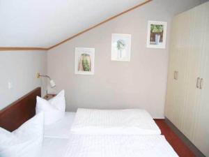 a bedroom with two white beds and pictures on the wall at Apartment für den perfekten Urlaub in Granzow +26 photos