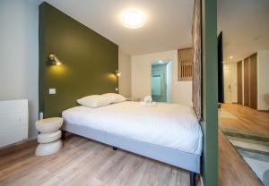 Un dormitorio con una cama y una pared verde. en Le Splendide, en Mâcon