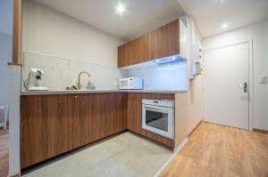 una pequeña cocina con armarios de madera y microondas en Le Splendide, en Mâcon