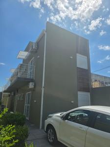 a white car parked in front of a building at JK POUSADA FLATS EXECUTIVE GARAGEM central in Pelotas