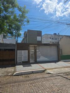 a building with a garage with a gate and a door at JK POUSADA FLATS EXECUTIVE GARAGEM central in Pelotas