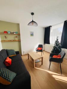 een woonkamer met een bank en 2 stoelen en een kerstboom bij A l'orée des bois in Égat