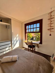 Un dormitorio con una cama y una ventana y una silla. en Casa Örüm, en Florianópolis