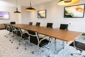 ein Konferenzraum mit einem großen Holztisch und Stühlen in der Unterkunft Placemakr Huntsville - MidCity District in Huntsville + 100 Fotos