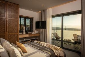 a bedroom with a bed and a balcony with a view at Brand new Petra Luxuria Villa with private pool in Prasás