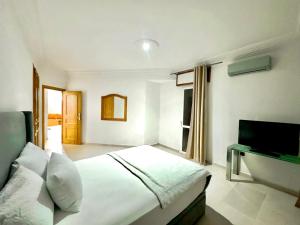 Modern and Cozy Beach Facing 2BR Apt in La Tulipe Complex, Tangier في Charf: غرفة نوم مع سرير وتلفزيون بشاشة مسطحة
