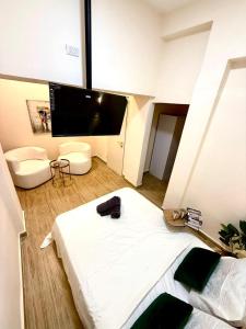 Un dormitorio con una gran cama blanca y un televisor de pantalla plana. en Irooms770, en Haifa