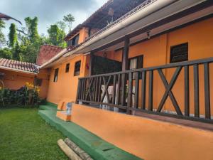 een oranje gebouw met een balkon met een tuin bij Chalé da Elba 01 Ilhabela in Ilhabela