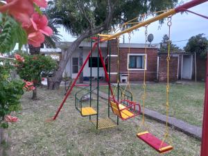 a swing set in a yard with a house at Corbeta in Piriápolis