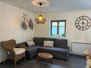 ein Wohnzimmer mit einer Couch und einer Uhr an der Wand in der Unterkunft Sand & Chill - Appartement 55R in Rouffach + 1 Foto