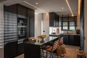 a kitchen with black cabinets and a table and chairs at Brand new Petra Luxuria Villa with private pool in Prasás