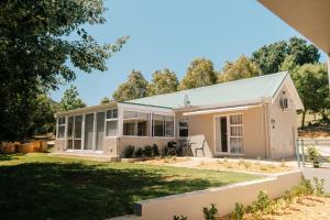 a small white house with a green roof at Patryssenvalleij Farm and Cottages in Stellenbosch