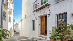Casa Al Zaytun Pueblo في Canillas de Aceituno: منزل أبيض مع باب خشبي ونباتات الفخار