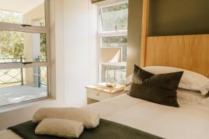 a bedroom with a bed and two windows at Patryssenvalleij Farm and Cottages in Stellenbosch