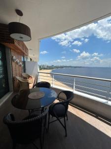 een balkon met een tafel en stoelen en uitzicht op de oceaan bij Tropical Executive Flat Vista da Orla in Manaus