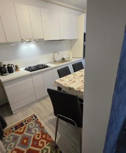 a kitchen with white cabinets and a table and chairs at Apartament Zen Home in Craiova +3 photos