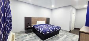 a bedroom with a bed with a blue and white blanket at Airway Inn - IAH Airport in Houston
