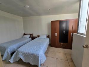 een slaapkamer met twee bedden, een kast en een raam bij Los Nogales LS in Lima