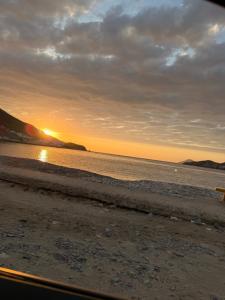 un coucher de soleil sur la plage avec un banc sur la plage dans l'établissement Mar Apart Hotel, à Casma
