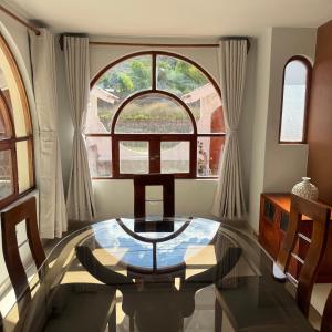 a dining room with a glass table and a large window at Shumaq Guesthouse in Carhuaz