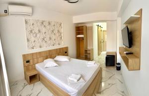 ein kleines Schlafzimmer mit einem weißen Bett und einem TV in der Unterkunft Pensiunea Duet in Sărata-Monteoru