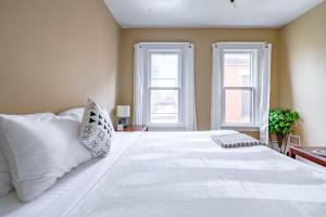 una camera da letto con un grande letto bianco con due finestre di Jungle House Luxury Stays - Columbus Downtown Short North a Columbus