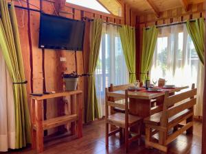 a dining room with a wooden table and a television at CABAÑAS RACO in Licán Ray
