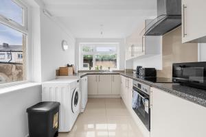 a white kitchen with a sink and a dishwasher at Modern 4BR Parking in Manchester +20 photos