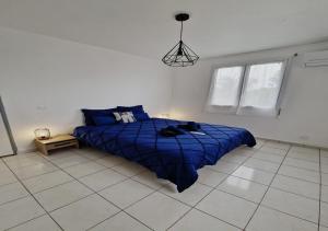 a bedroom with a blue bed in a white room at La Casa Bongo - T4 cosy en pleine nature in Capesterre-Belle-Eau