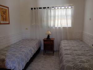 two beds in a bedroom with a table and a window at Casa Serrana Punilla in Santa María +3 photos