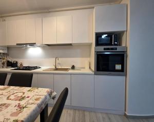 a kitchen with white cabinets and a microwave and a table at Apartament Zen Home in Craiova