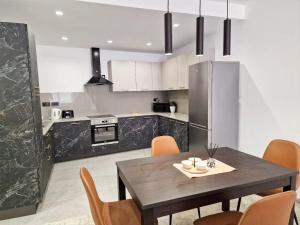 Luxury Qawra Holiday Stay Apartment في خليج سانت بول: مطبخ مع طاولة وكراسي وثلاجة
