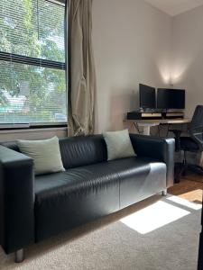 a black leather couch in a living room with a window at Cozy Home away from home! in Miami