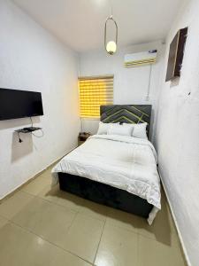 sypialnia z łóżkiem i telewizorem z płaskim ekranem w obiekcie Crestal Resorts w mieście Magodo