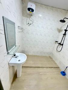 biała łazienka z umywalką i lustrem w obiekcie Crestal Resorts w mieście Magodo +3 zdjęcia