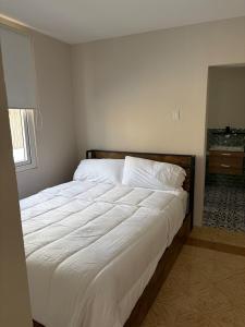 a bedroom with a bed with white sheets and a window at Mereri downtown apartments, apartment 13C in Oranjestad