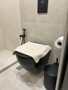 Un baño con un inodoro negro con una toalla encima. en Elite Suite, en Xanthi