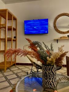 ein Wohnzimmer mit einem Tisch und einem Fernseher an der Wand in der Unterkunft Dar Koutobia Stars in Marrakesch