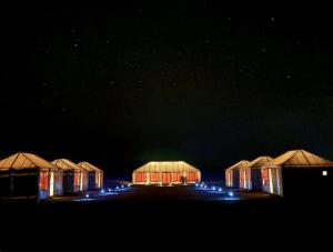 a row of huts lit up at night at Arawan Luxury Desert Camp in Mhamid