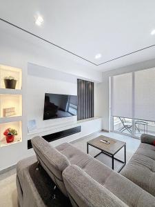 Luxury Qawra Holiday Stay Apartment في خليج سانت بول: غرفة معيشة مع أريكة وتلفزيون بشاشة مسطحة