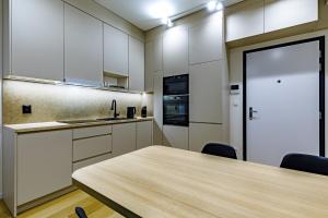 Apartmán Mierova في براتيسلافا: مطبخ مع دواليب بيضاء وطاولة مع كراسي +16 صورة