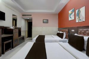 Una habitación de hotel con dos camas y un televisor. en Collection O Haridwar Railway Station Formerly Le Central, en Haridwar