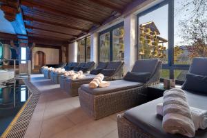 a row of chairs and couches on a porch at Alpin & Wellness Resort Ludwig Royal in Oberstaufen